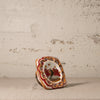 Small ceramic piece with decorative design on a textured surface