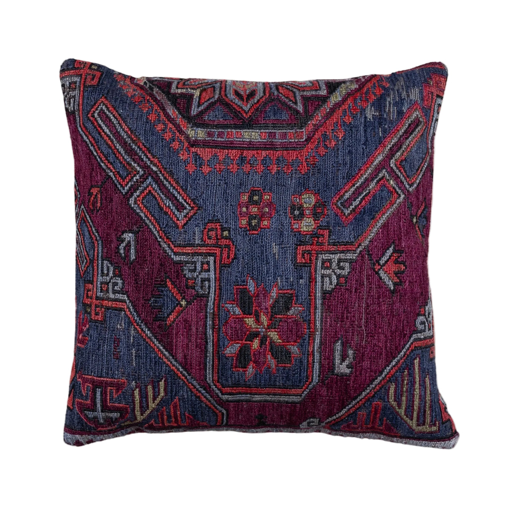 A square throw pillow featuring a detailed, vintage-style geometric and floral pattern in deep navy blue, magenta, and red, set against a plain off-white background.