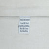 A close-up of a white woven fabric label sewn onto a light gray or off-white textile, showing text that reads 'MADE IN TURKEY', 'Front 100% Wool', 'Hand Woven Old Kilim', 'Back 100% Cotton', and 'DryCleanOnly'.