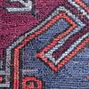 Close-up of a woven textile pattern with layered geometric shapes in dusty blue, burgundy, coral red, and gray.
