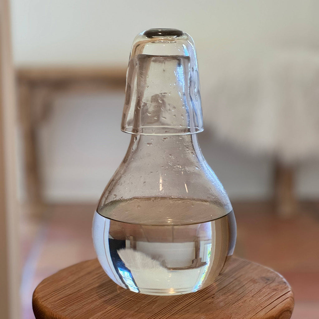 Clear glass carafe on a wooden stool with a blurred background