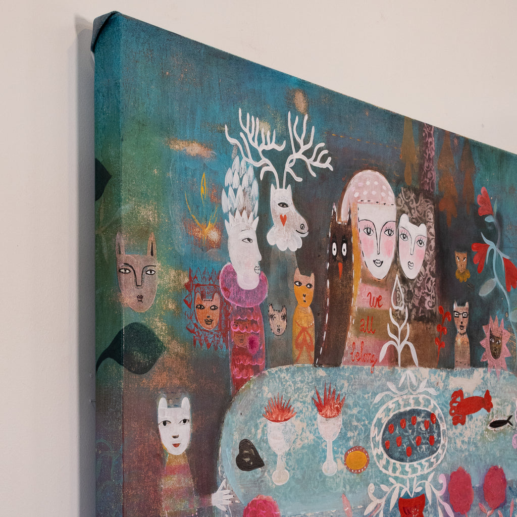A square canvas painting shown at an angle against a plain light wall. The artwork features stylized faces, animals, and abstract forms in teal, blue, brown, white, pink, red, and orange tones.