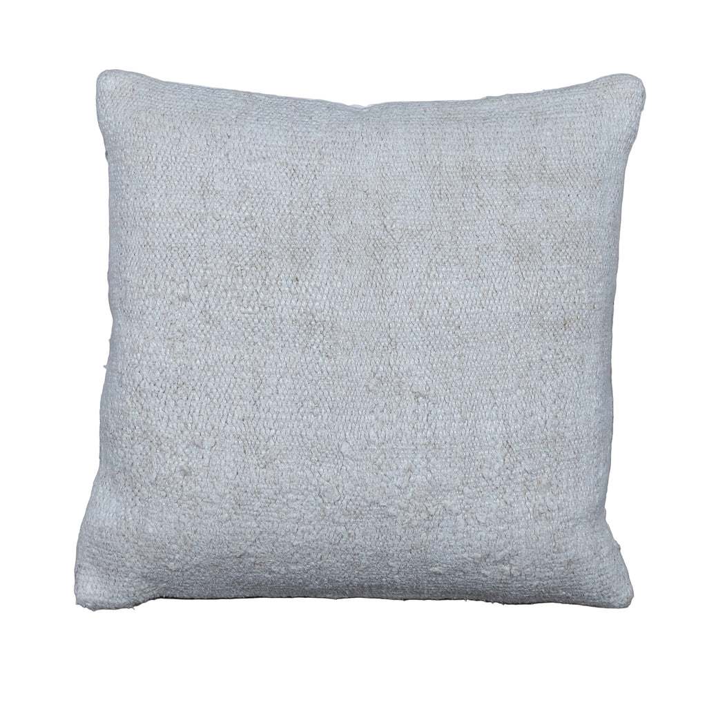A square throw pillow in a textured, woven off-white fabric, displayed flat on a rustic gray wooden plank floor.
