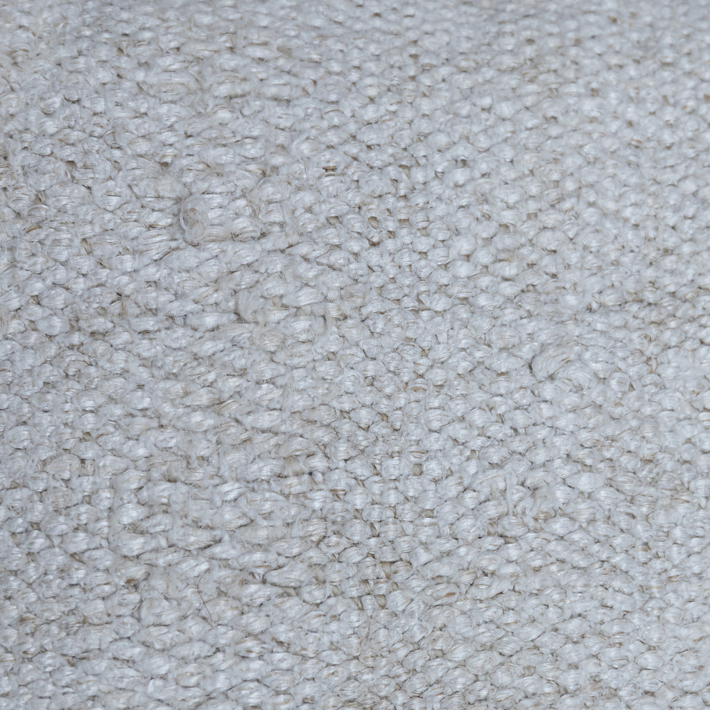 A close-up texture shot of a light beige or off-white loop-pile carpet or rug, showing the detailed woven fibers.