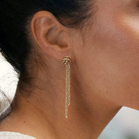 Close-up of a gold chain earring worn by a person with a blurred background