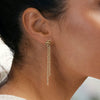 Close-up of a gold chain earring worn by a person with a blurred background