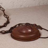 A vintage rusted metal ceiling light fixture canopy with a chain, shown on a neutral textured surface.