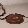 A vintage rusted metal ceiling light fixture canopy with a chain, shown on a neutral textured surface.