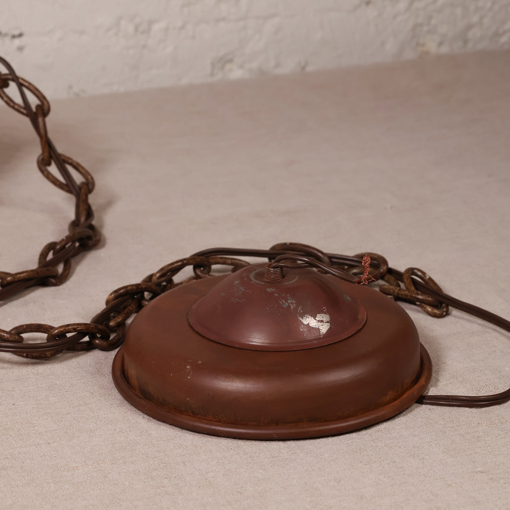 A vintage rusted metal ceiling light fixture canopy with a chain, shown on a neutral textured surface.