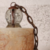 Close-up of a vintage-style hanging lamp with a clear glass globe bulb, dark metal chain, and a cream-colored textured shade.