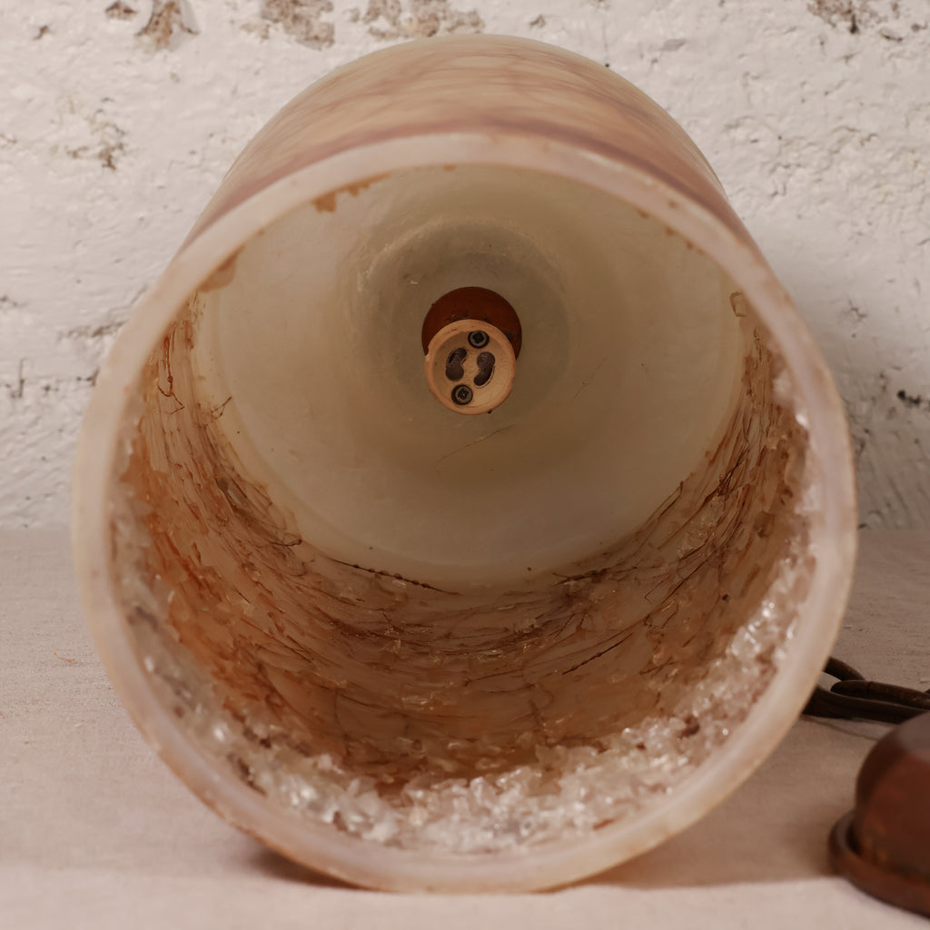 Close-up of the interior of a vintage-style bell-shaped lamp shade made of textured, warm-toned glass, showing the brass socket at the top and a textured off-white background.