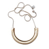 Gold necklace with a large curved pendant on a light gray background