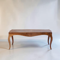 A mid-century wooden console table with a curved apron and cabriole legs, shown against a plain off-white studio background.