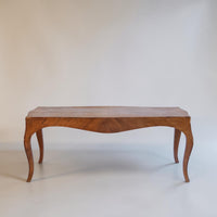A mid-century wooden console table with a curved apron and cabriole legs, shown against a plain off-white studio background.