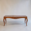 A mid-century wooden console table with a curved apron and cabriole legs, shown against a plain off-white studio background.