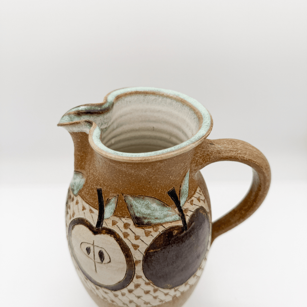 Ceramic pitcher with apple design on a white background