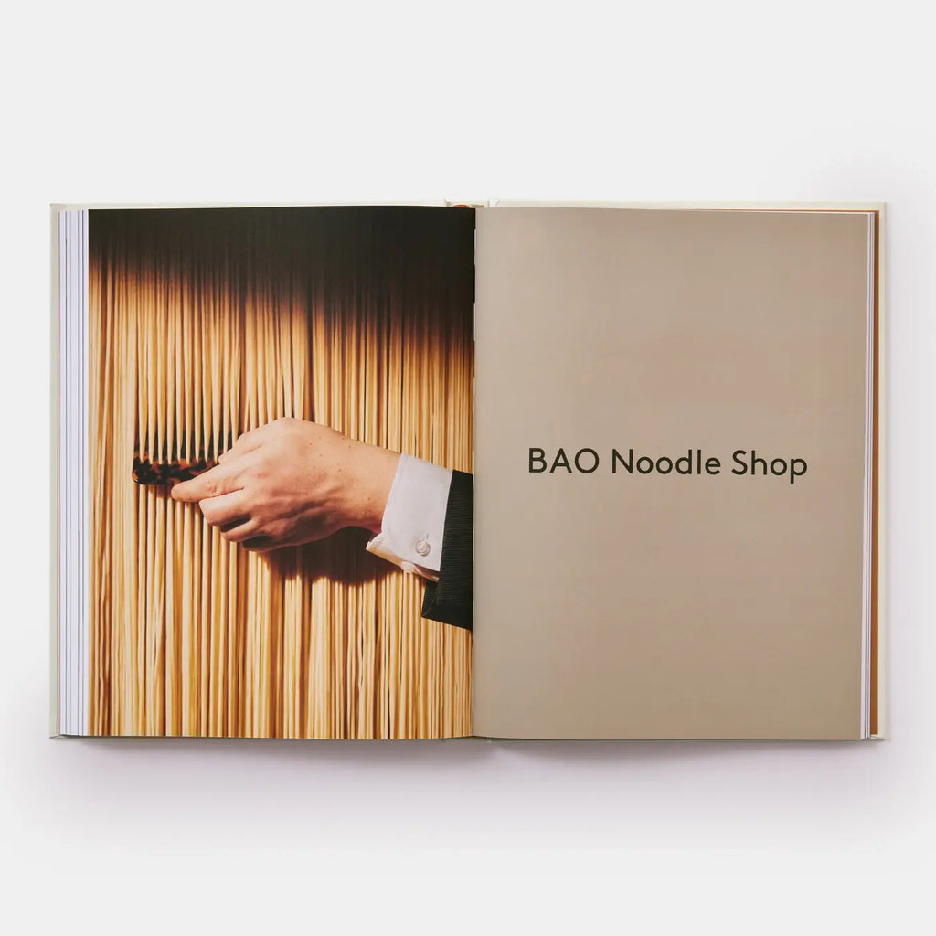 Open book showing a hand holding noodles with 'BAO Noodle Shop' text on a white background