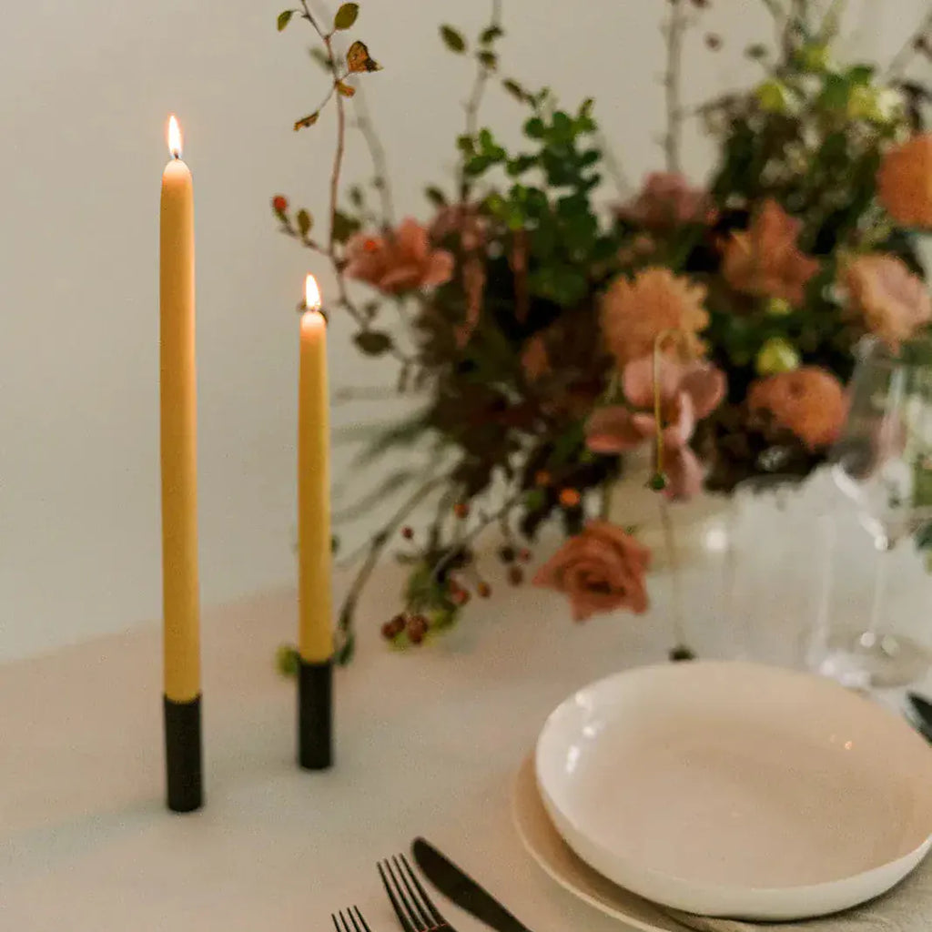 Two lit candles, flowers, and a place setting.