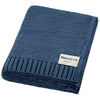 Folded blue knit blanket with a visible brand label on a white background