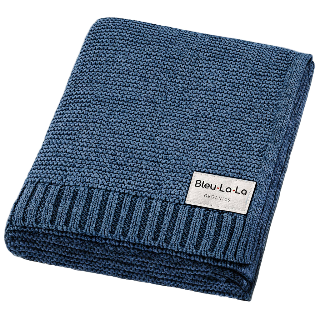 Folded blue knit blanket with a visible brand label on a white background