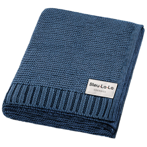 Folded blue knit blanket with a visible brand label on a white background
