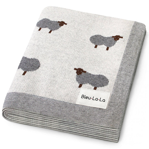 Folded blanket with sheep pattern and 'Bleu-La-La' label on a white background