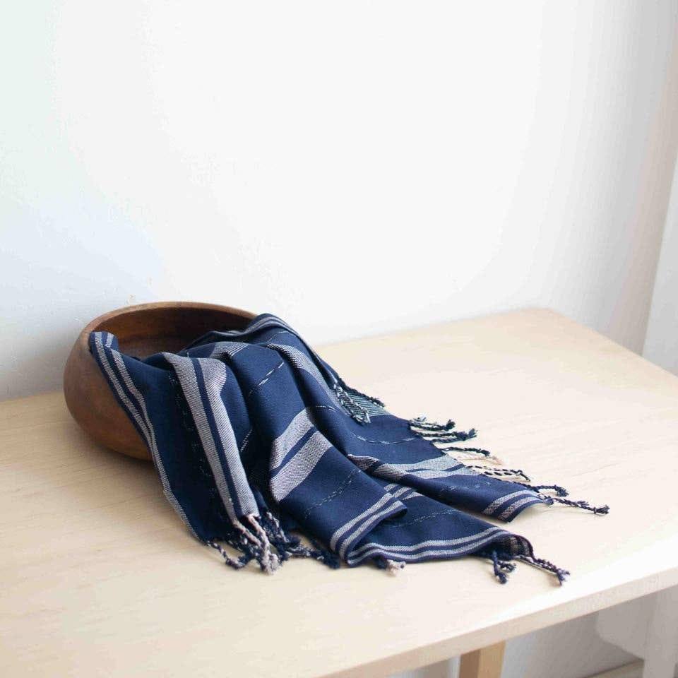 Blue and gray striped scarf on a wooden surface with a white background