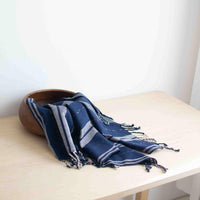 Blue and gray striped scarf on a wooden surface with a white background