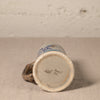 Ceramic mug with blue design on beige surface and textured background