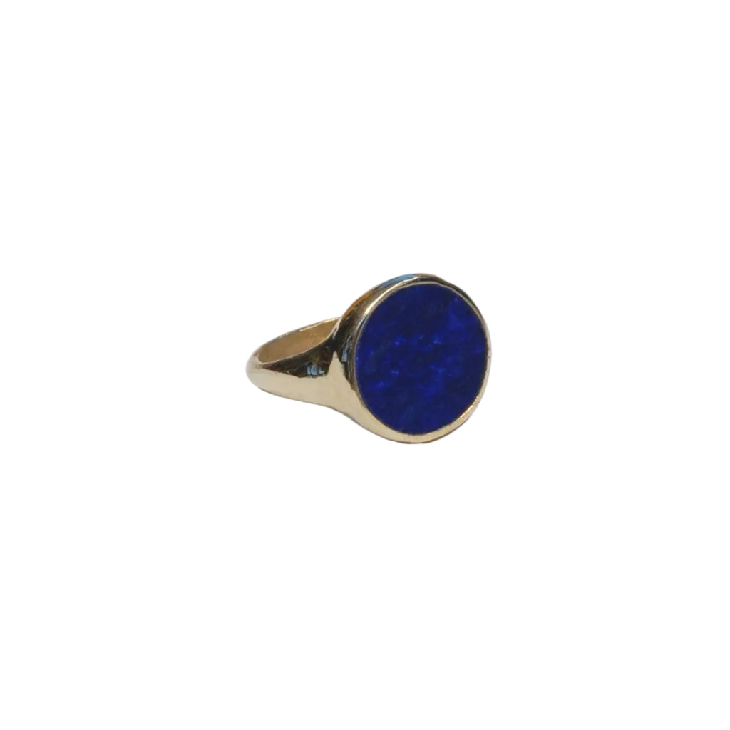 Gold ring with a blue stone on a light gray background