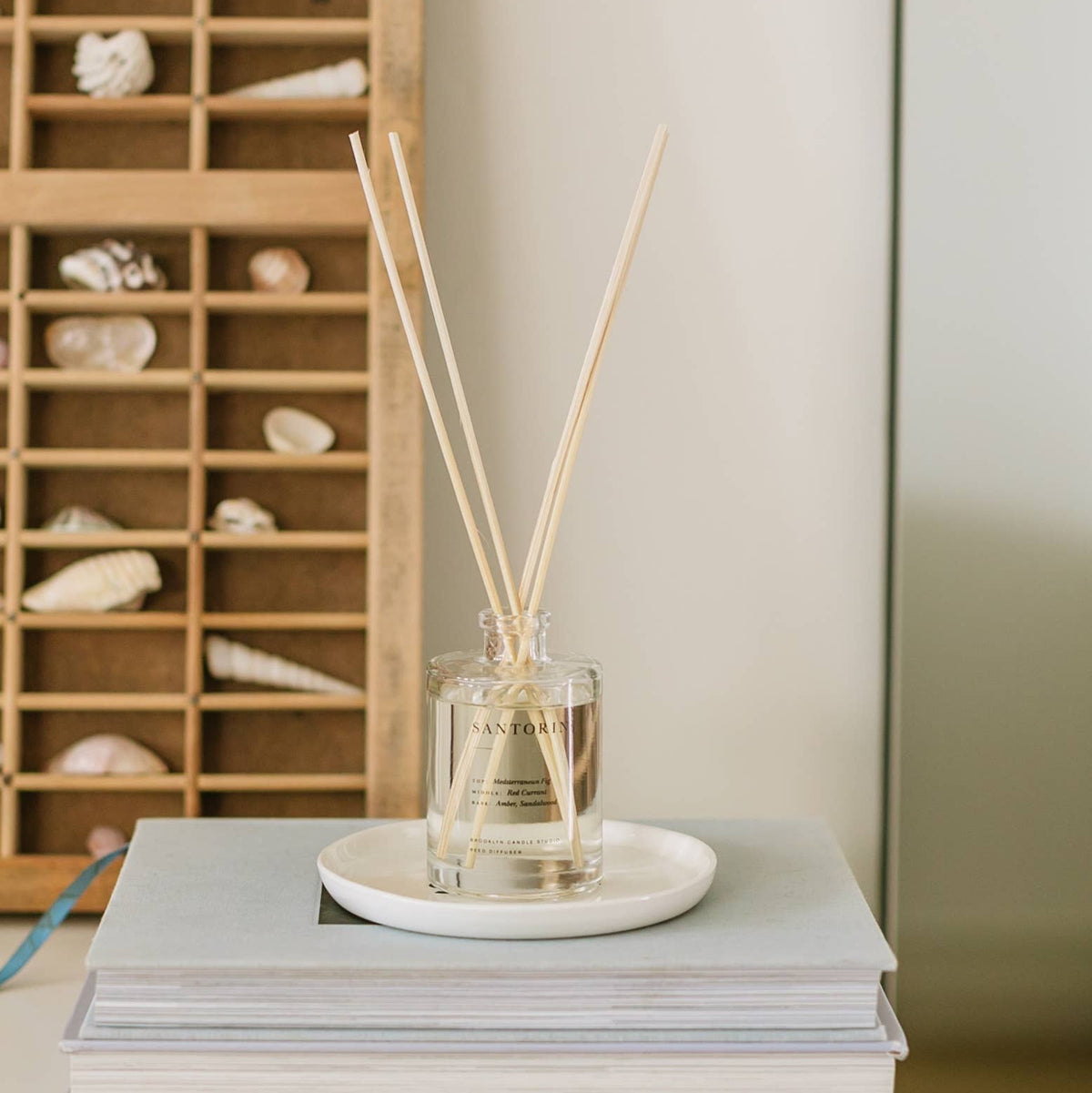 Reed diffuser on a stack of books with a wooden shelf in the background