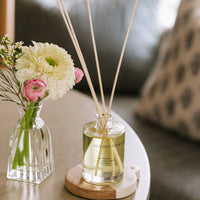 A diffuser with reeds and a small vase of flowers on a table.