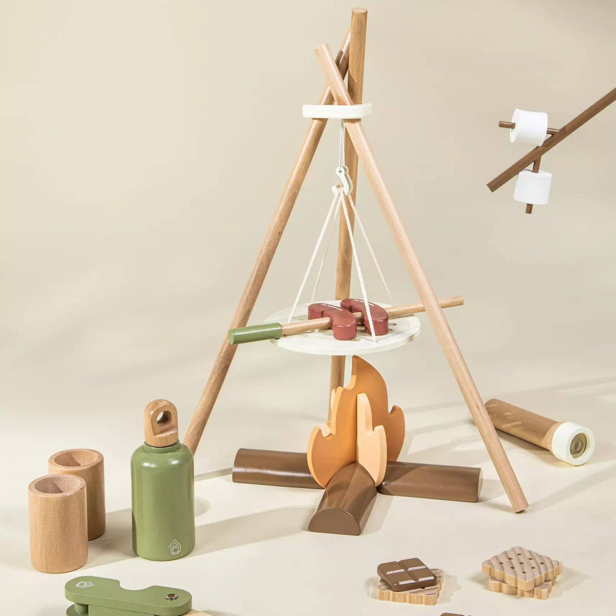 Wooden play set with a teepee structure, campfire, and accessories on a beige background
