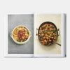 Open cookbook showing two recipes, one in a white dish and the other in a metal pan with vegetables.