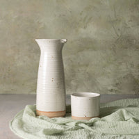Two ceramic vases on a textured surface with a neutral background