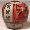 A small hand-painted ceramic pot with a rounded shape, featuring a red and brown abstract geometric pattern on a cream and brown glazed base.