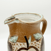 Ceramic pitcher with decorative elements on a white background