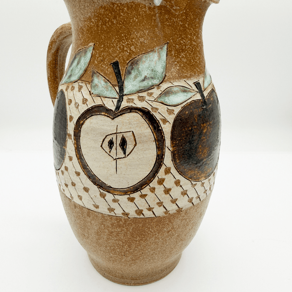 Ceramic pitcher with apple design on a white background