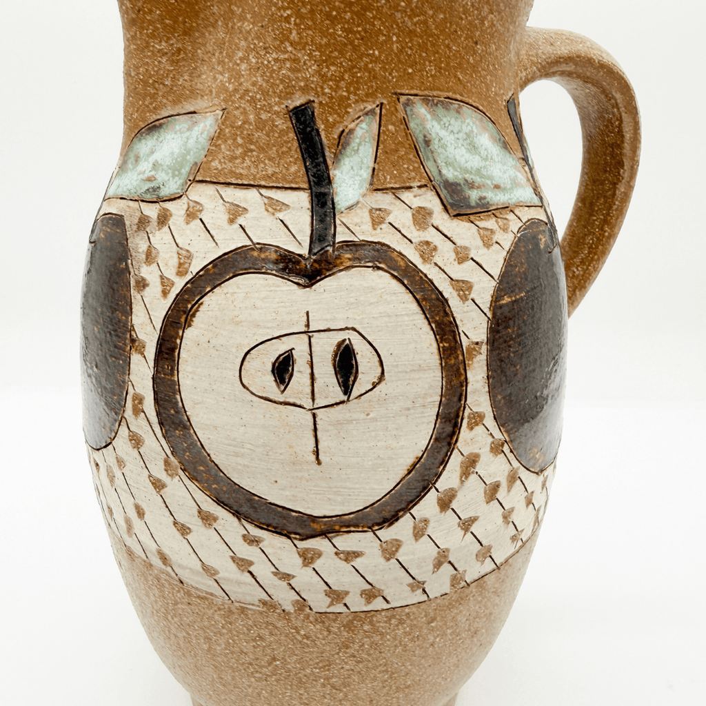 Ceramic pitcher with apple design on a white background