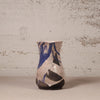 Ceramic vase with blue and black abstract design on a textured surface