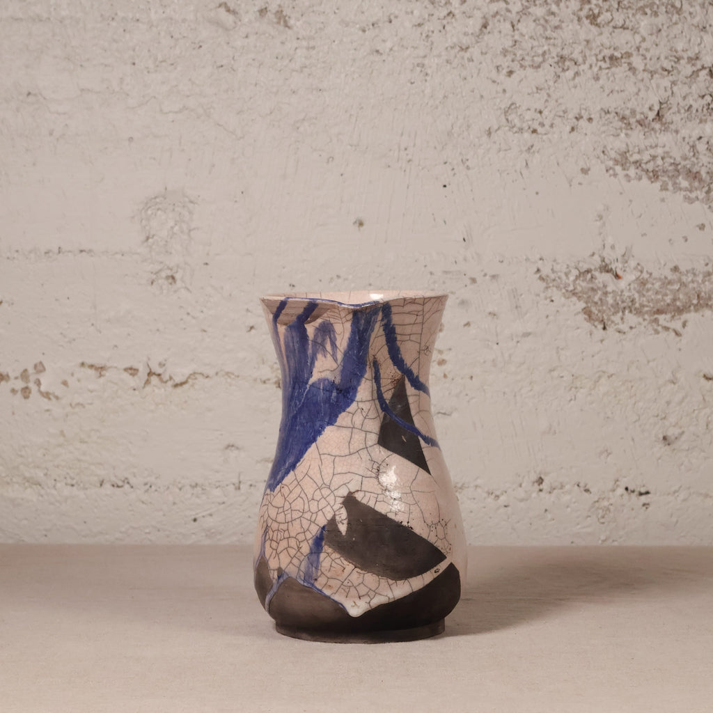 Ceramic vase with blue and black abstract design on a textured surface
