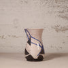 A handmade ceramic vase with a textured, hand-painted finish. The vase features a glossy off-white glaze with prominent black geometric shapes and a striking blue crackle pattern running diagonally across the surface.