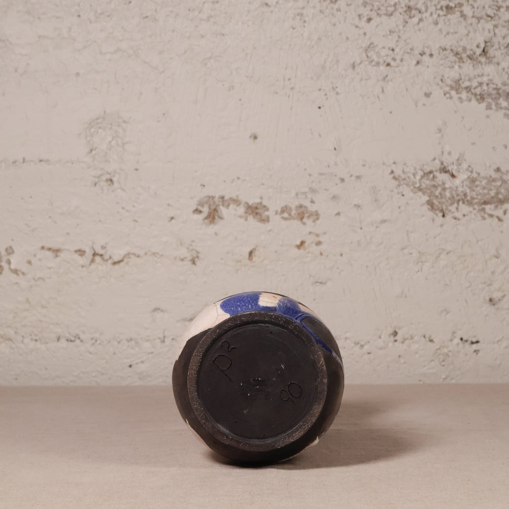 Ceramic vase with blue and white pattern on a textured beige surface