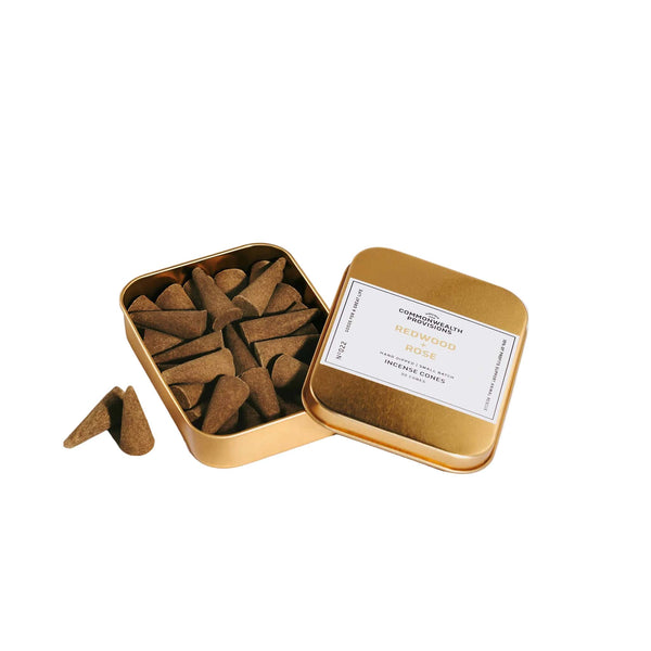 Open gold tin containing incense cones with a visible label on a white background