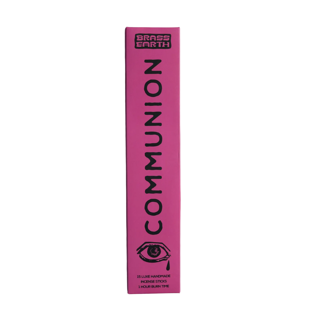 A tall, narrow pink box for Brass Earth Communion skincare stands vertically against a matching pink background. The box features black text reading 'BRASS EARTH COMMUNION' and a black eye illustration near the bottom.