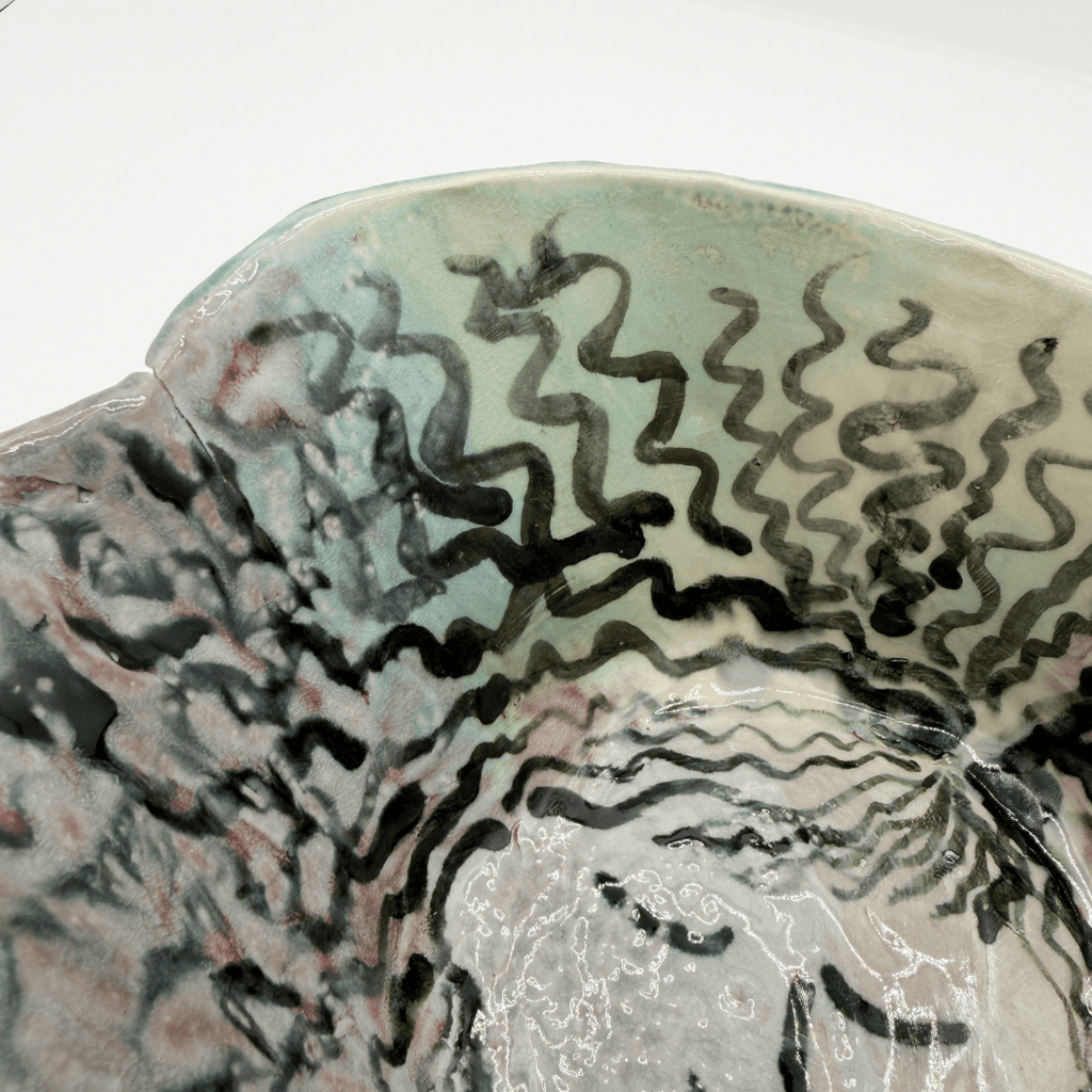 Close-up of a ceramic bowl with wavy black lines on a white background