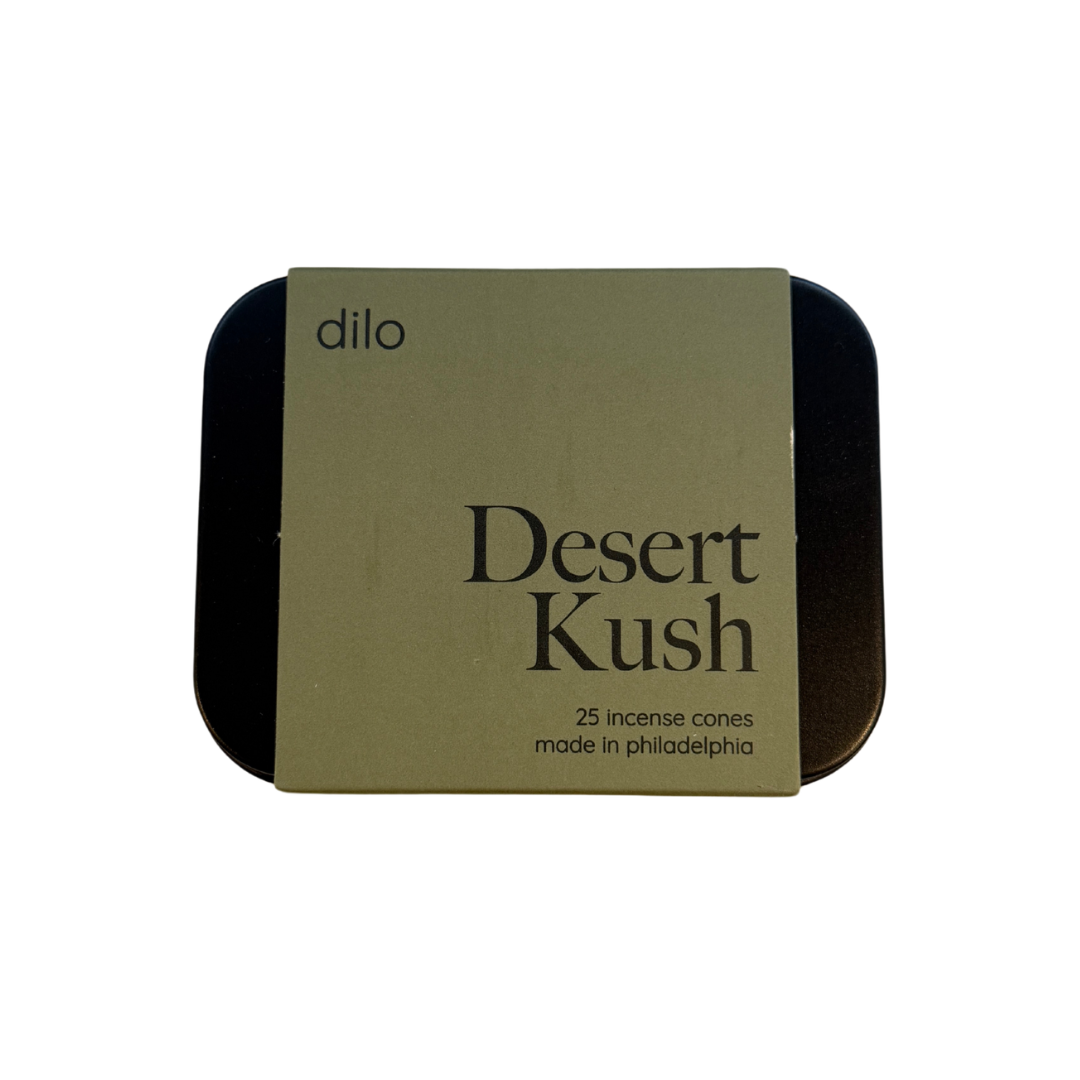 A square metal tin of Dilo Desert Kush incense cones, featuring a tan paper label with black text, set against a plain white background.