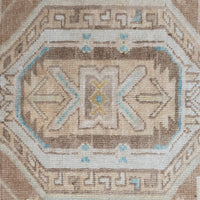 A close-up of a woven textile or rug pattern with an octagonal medallion design in beige, brown, cream, light blue, and small yellow accents.