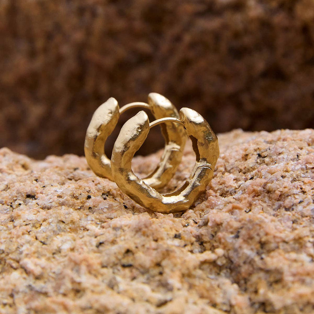 Gold hoop earring on a textured brown surface