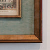Close-up of a framed vintage print on a textured wall.